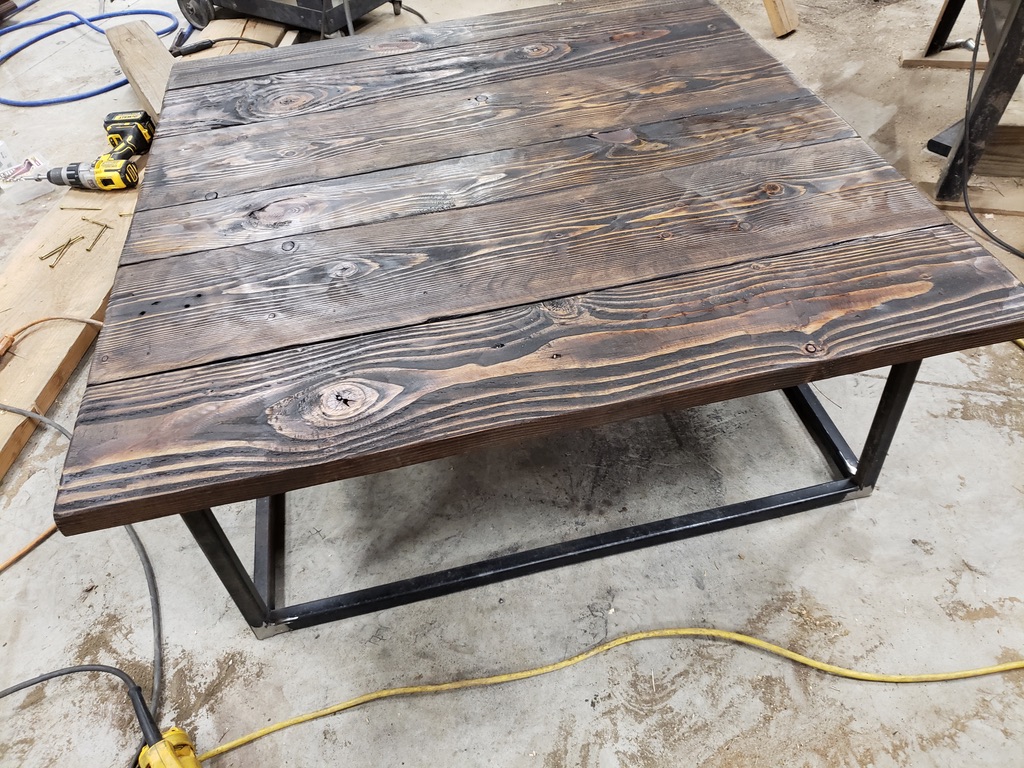 Rustic coffee table with dark-stained wood plank top on a custom welded steel rectangular frame base