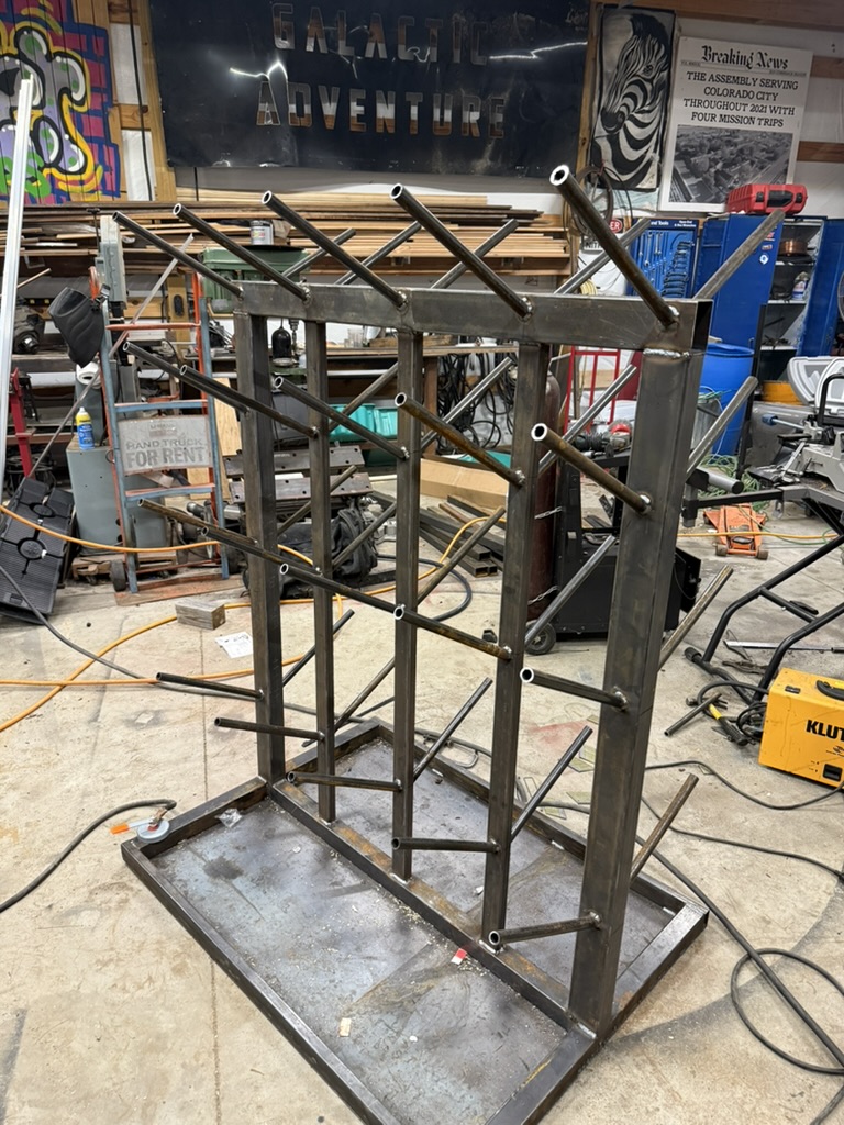 Custom welded steel storage and display rack with multiple tiers being fabricated in welding shop
