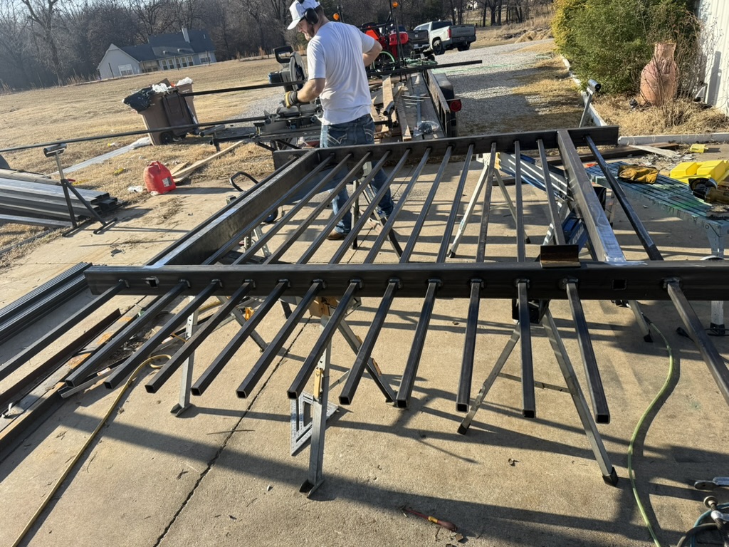 Dream Weaver Construction owner cutting steel with a chop saw during fence panel fabrication