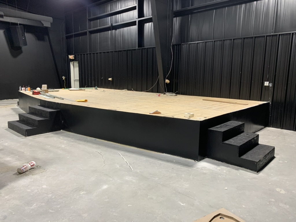 Custom built steel-framed stage platform with steps painted black in a commercial worship venue