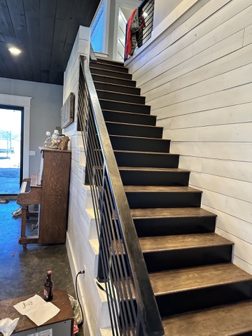 Custom welded steel staircase railing with vertical balusters in modern farmhouse interior with shiplap walls